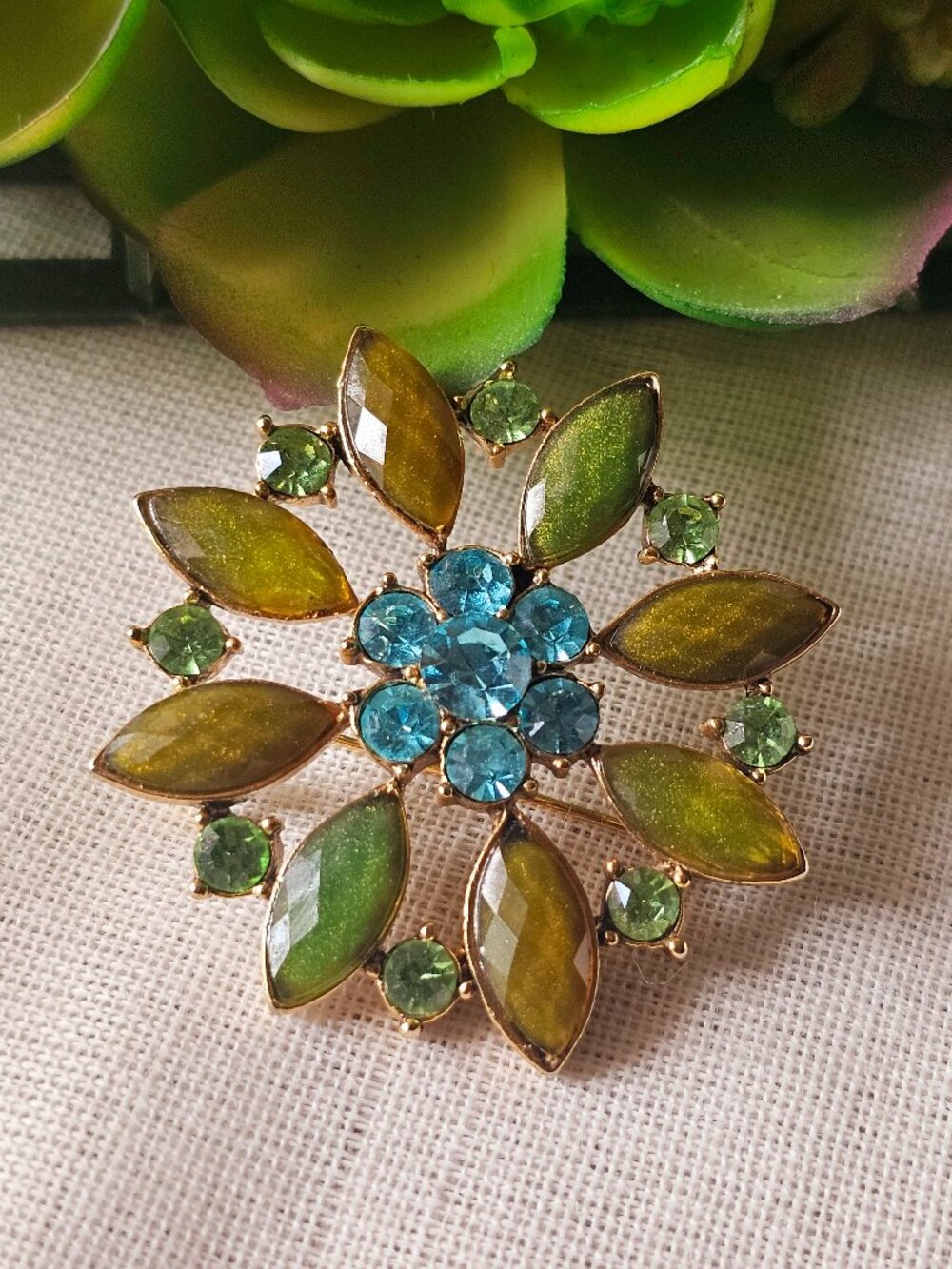 Fashion jewelry floral pin brooch with blue and green stones over gold-tone